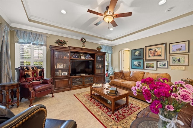 tiled living room featuring crown molding, a raised ceiling, and ceiling fan