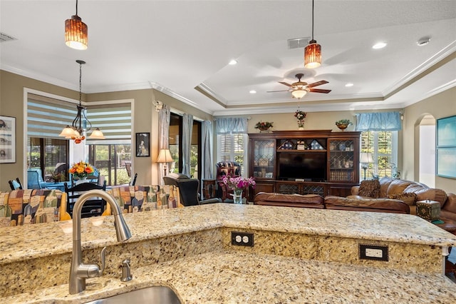 kitchen with light stone counters, sink, and decorative light fixtures