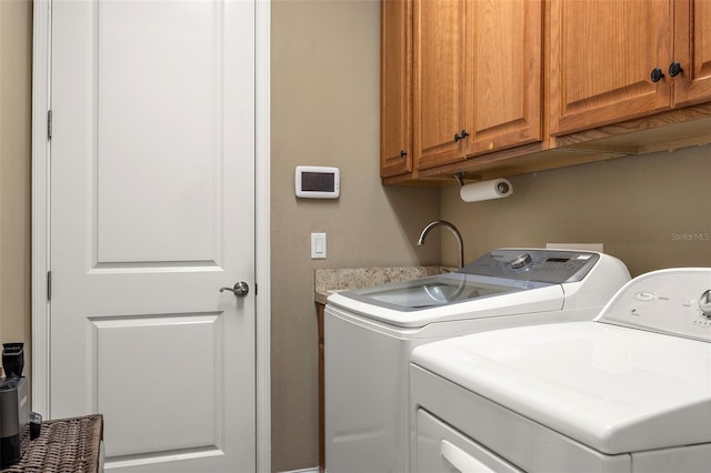 clothes washing area with cabinets and washing machine and clothes dryer