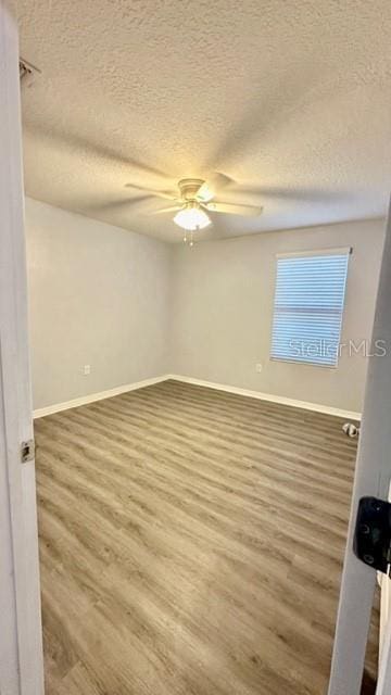 empty room with ceiling fan, hardwood / wood-style floors, and a textured ceiling