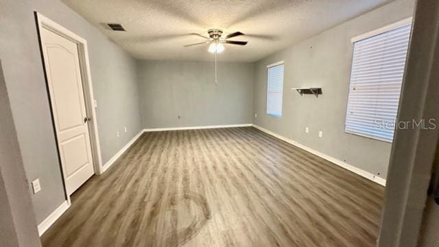 empty room with hardwood / wood-style flooring, ceiling fan, and a textured ceiling