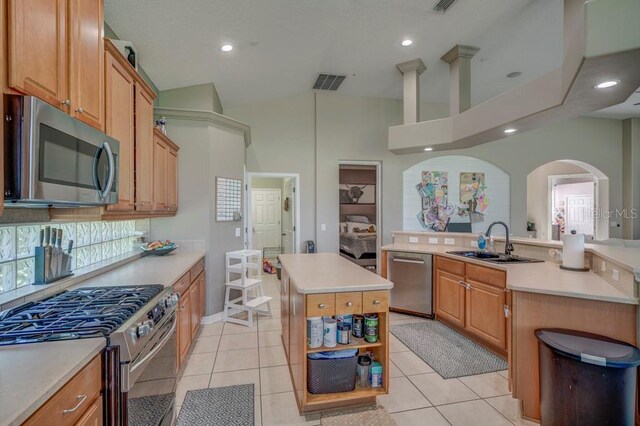 kitchen featuring sink, light tile patterned floors, a towering ceiling, appliances with stainless steel finishes, and a kitchen island