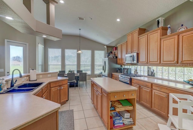 kitchen with stainless steel appliances, vaulted ceiling, sink, pendant lighting, and a kitchen island