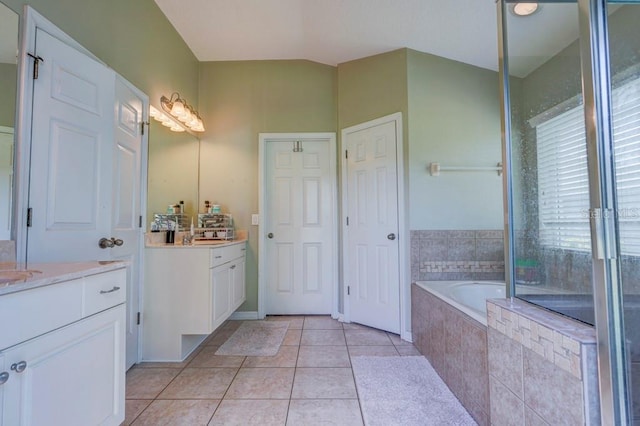 bathroom with tile patterned flooring, vanity, and tiled tub