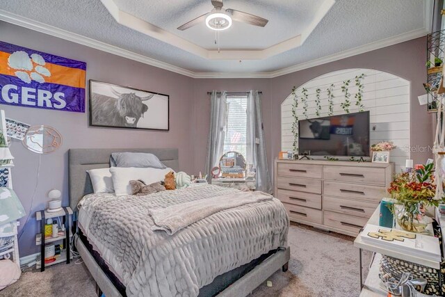 carpeted bedroom with a textured ceiling, a raised ceiling, and ceiling fan