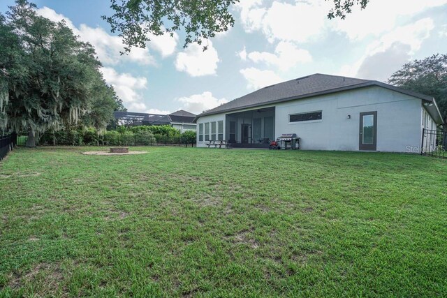 view of yard featuring a sunroom and an outdoor fire pit