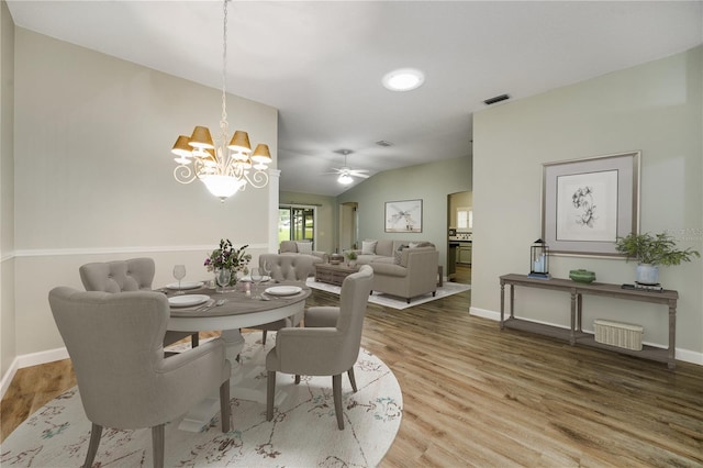 dining room with lofted ceiling, hardwood / wood-style floors, and ceiling fan with notable chandelier