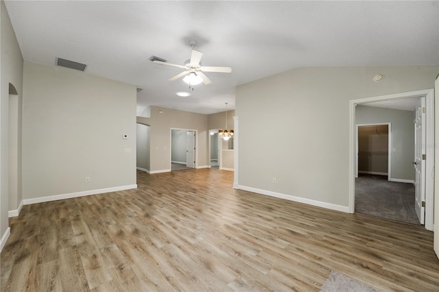 unfurnished living room featuring baseboards, ceiling fan with notable chandelier, wood finished floors, and visible vents