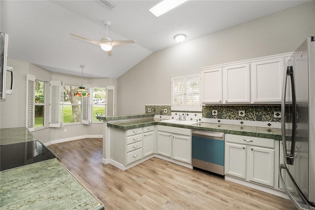 kitchen with freestanding refrigerator, a peninsula, lofted ceiling, a sink, and dishwasher