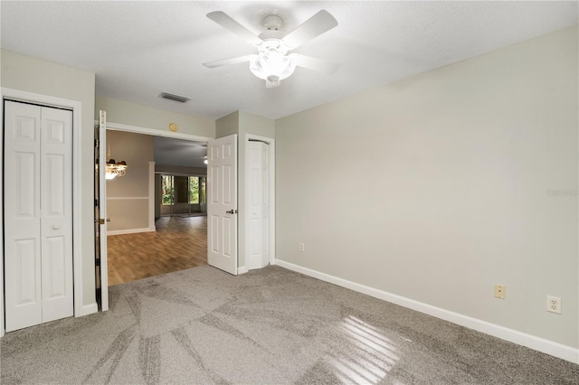 unfurnished bedroom featuring visible vents, carpet flooring, multiple closets, and baseboards