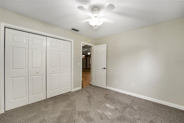 unfurnished bedroom with a closet, ceiling fan, carpet flooring, and a textured ceiling