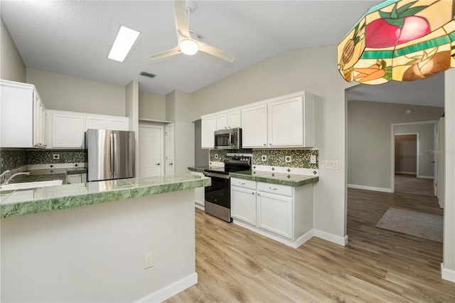 kitchen with appliances with stainless steel finishes, visible vents, light wood finished floors, and lofted ceiling