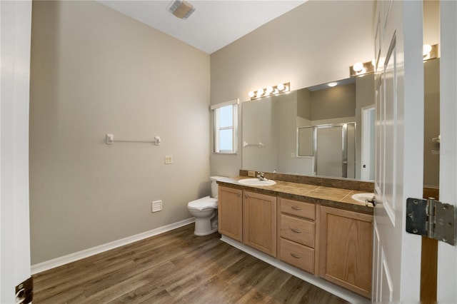 bathroom with double vanity, wood finished floors, toilet, a shower stall, and a sink