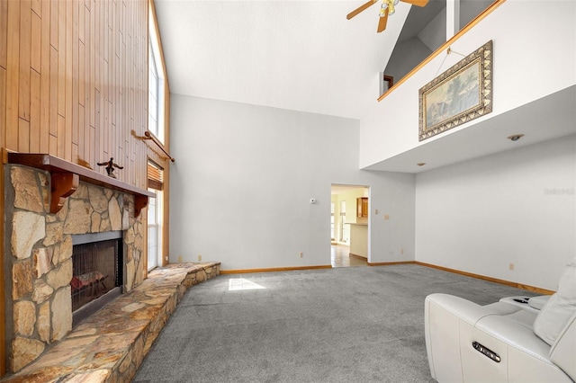 unfurnished living room with a stone fireplace, carpet floors, ceiling fan, and a towering ceiling