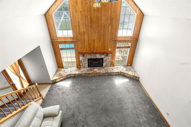 unfurnished living room with a stone fireplace, a towering ceiling, a textured ceiling, and carpet