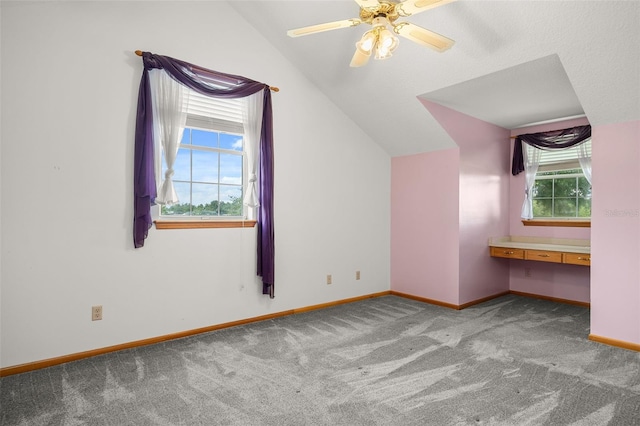 bonus room with light carpet, built in desk, vaulted ceiling, and ceiling fan