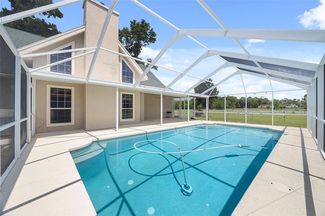 view of pool with glass enclosure and a patio area