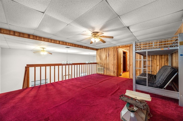 interior space with ceiling fan with notable chandelier, carpet floors, and wood walls