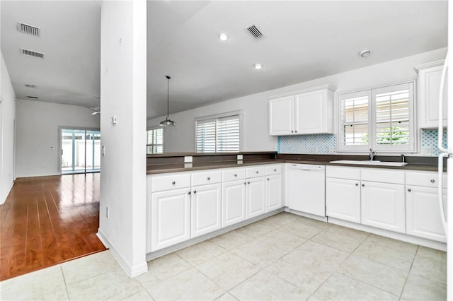 kitchen featuring light wood-type flooring, white dishwasher, hanging light fixtures, and decorative backsplash