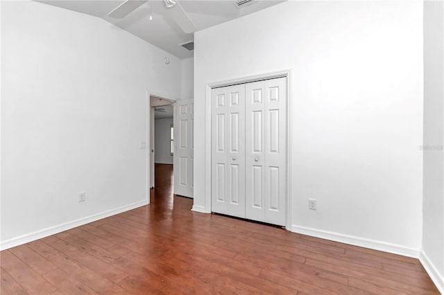 unfurnished bedroom featuring hardwood / wood-style floors, high vaulted ceiling, a closet, and ceiling fan