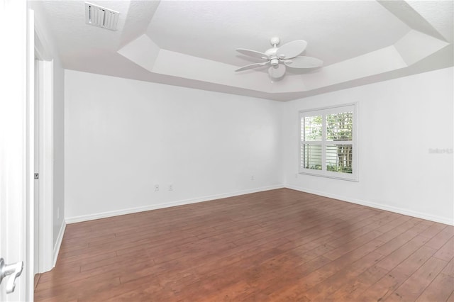 unfurnished room featuring a textured ceiling, a tray ceiling, hardwood / wood-style floors, and ceiling fan