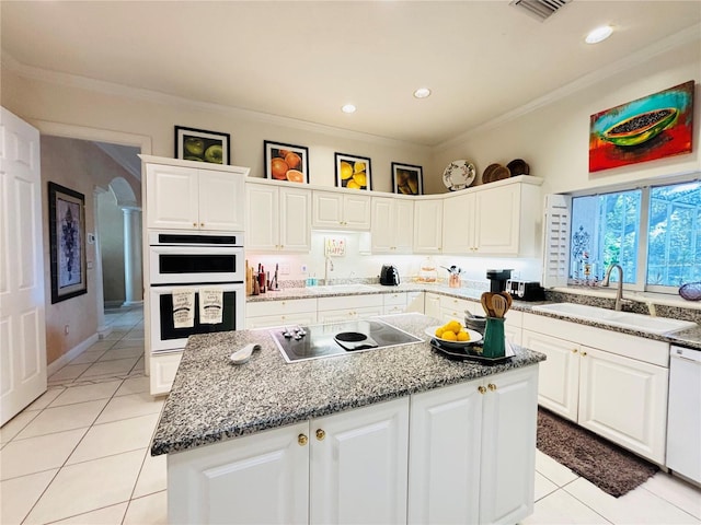 kitchen with white appliances, a center island, white cabinetry, sink, and light tile patterned flooring