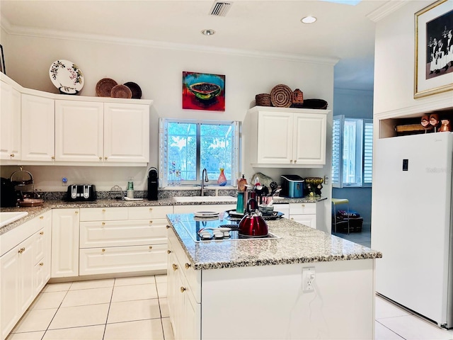 kitchen with white cabinetry, black electric stovetop, white refrigerator, and a center island