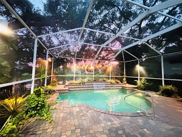 view of swimming pool featuring glass enclosure and a patio