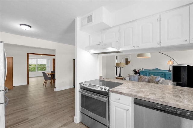 kitchen with appliances with stainless steel finishes, white cabinets, and light hardwood / wood-style flooring