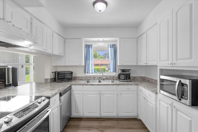 kitchen with sink, light wood-type flooring, white cabinets, and appliances with stainless steel finishes