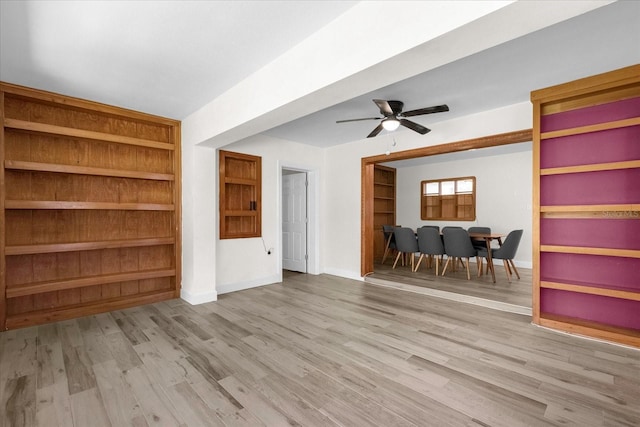 unfurnished living room with built in shelves, light hardwood / wood-style floors, and ceiling fan