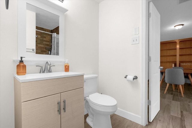 bathroom featuring wood-type flooring, toilet, curtained shower, and vanity