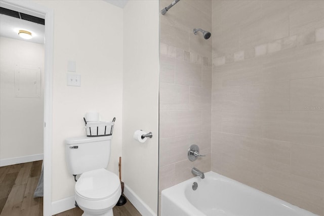 bathroom featuring hardwood / wood-style flooring, electric panel, toilet, and tiled shower / bath