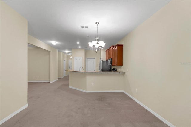 kitchen featuring a notable chandelier, appliances with stainless steel finishes, light colored carpet, and hanging light fixtures