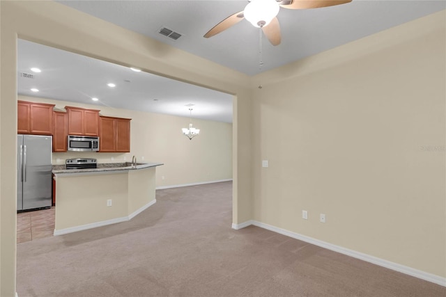 kitchen featuring hanging light fixtures, ceiling fan with notable chandelier, light carpet, a kitchen island, and appliances with stainless steel finishes