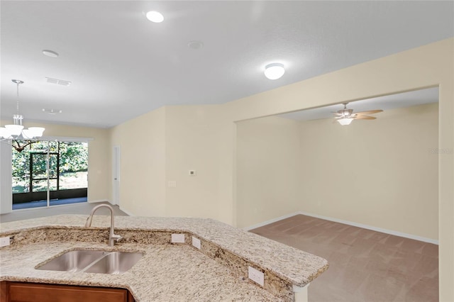 kitchen featuring sink, carpet, ceiling fan with notable chandelier, and light stone countertops