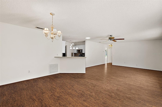 unfurnished living room with ceiling fan with notable chandelier, dark hardwood / wood-style floors, and a textured ceiling