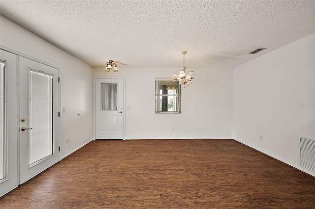 empty room with a textured ceiling and a notable chandelier