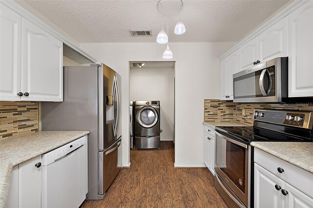 kitchen featuring appliances with stainless steel finishes, washer / clothes dryer, white cabinetry, and tasteful backsplash