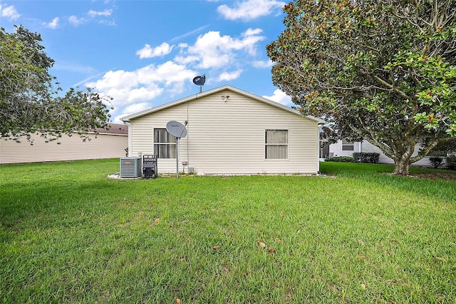 rear view of property featuring a lawn and central air condition unit