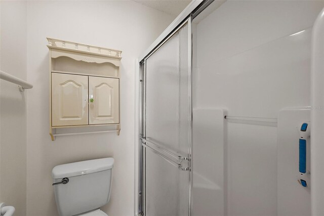 bathroom with toilet and an enclosed shower