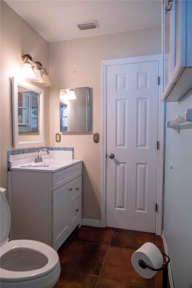 bathroom featuring visible vents, baseboards, toilet, vanity, and tile patterned flooring