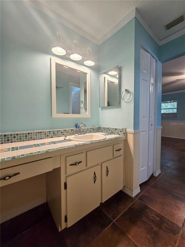 bathroom featuring vanity, ornamental molding, tile patterned floors, visible vents, and wainscoting
