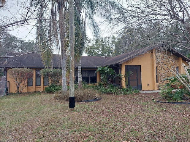 view of front of house with a front lawn, a shingled roof, and stucco siding