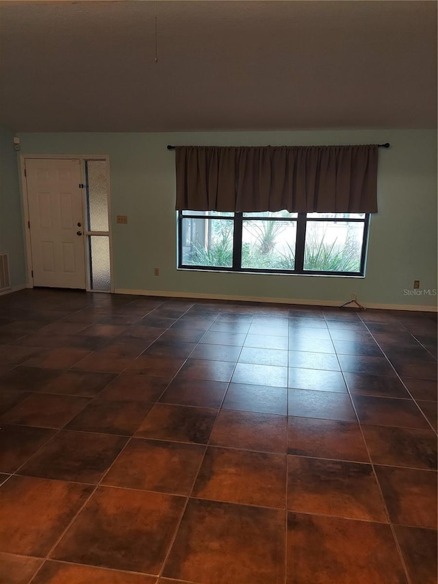 tiled empty room with baseboards and visible vents