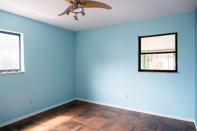 empty room featuring a ceiling fan and baseboards