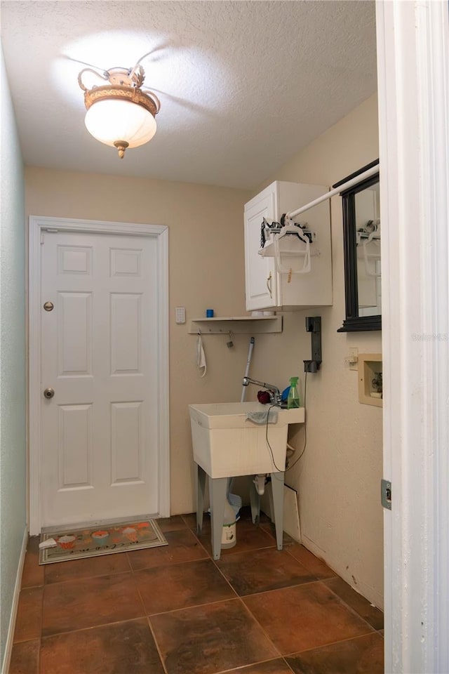 washroom with cabinet space, a textured ceiling, and washer hookup