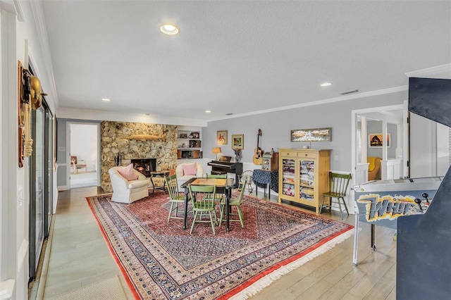 dining space with recessed lighting, visible vents, ornamental molding, a stone fireplace, and wood finished floors