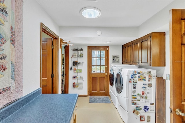 clothes washing area featuring separate washer and dryer and cabinet space