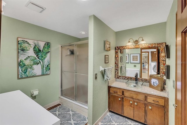 bathroom with a stall shower, washer / clothes dryer, visible vents, and baseboards